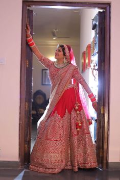 a woman in a red and gold bridal gown is holding her hand up to the door