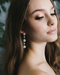 a woman with long brown hair wearing earrings