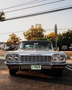 an old car is parked on the side of the road with power lines in the background