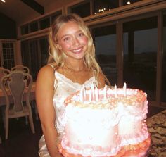 a woman standing in front of a cake with candles on it