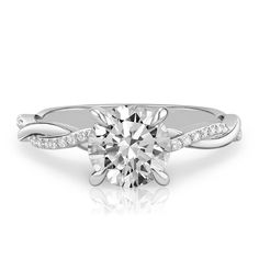 a white gold engagement ring with diamonds on the band and a round cut diamond in the center