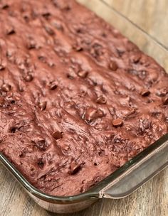 a chocolate cake in a glass baking dish on a wooden table with a spatula