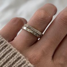 a woman's hand with a gold ring on top of her finger and two diamonds in the middle