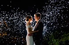 a bride and groom standing in front of fireworks