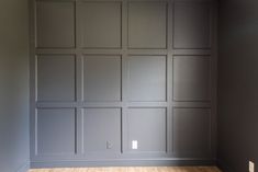 an empty room with gray walls and wood floors