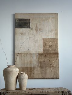 two white vases sitting on top of a wooden table next to a large painting