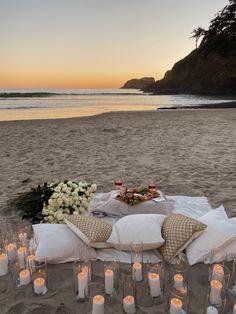 a table set up on the beach with candles