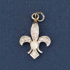 We recently acquired a batch of Deco-era charms that belonged to the same collector with a taste for diamonds, white metal, and yummy gemstone accents. This one is a diamond fleur de lis with a sweet pearl center, the size and spread of which we absolutely adore. Platinum & 18kt yellow gold .71 pennyweight Measures: 16.61 x 11.03mm .14ctw Diamonds are estimated to be G-I colors & SI clarities. GIA Standards Please see qualitative report for more information. Elegant Silver Wedding Charms, Elegant Wedding Charms With Vintage Style, Elegant Wedding Charms With Vintage Design, Elegant Vintage Wedding Charms, Vintage Silver Jewelry With Pearl Charm, Elegant Pendant Charms, Vintage White Gold Pendant Jewelry, White Gold Vintage Charm Pendant Jewelry, Antique White Gold Pearl Pendant Jewelry