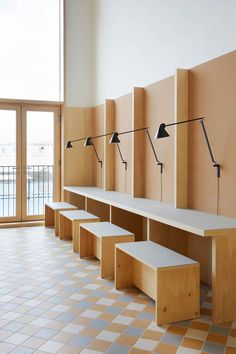 a row of wooden benches sitting next to each other on top of a tiled floor