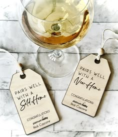 two wine tags sitting next to a glass of white wine on a marble counter top