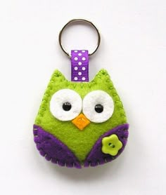 a green and purple owl keychain hanging from a hook