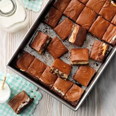 a pan filled with brownies next to a glass of milk