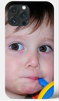 a young boy brushing his teeth with a toothbrush in front of him and looking at the camera