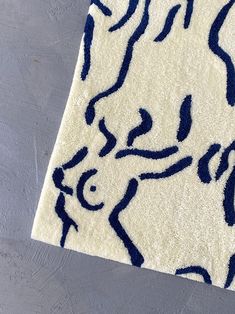 a white rug with blue and black designs on the floor next to a gray wall