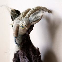 a stuffed animal that looks like a goat is hanging on the wall with it's head down