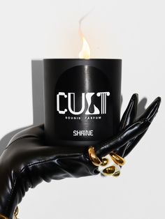 a hand holding a black candle with the word cusit on it in white lettering