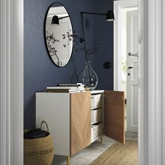 a blue room with a wooden cabinet and mirror on the wall, next to a wicker basket