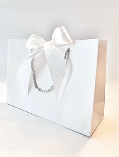 a white paper bag with a bow on it