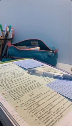 an open notebook sitting on top of a desk next to a pen and pencil holder