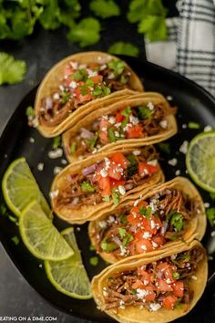 four tacos on a plate with limes and cilantro