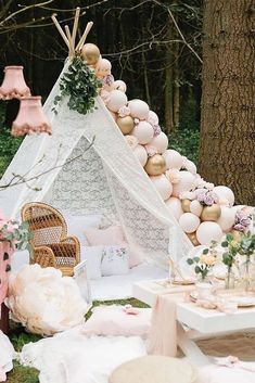 a teepee tent is set up in the woods for an outdoor party with pink and white decor