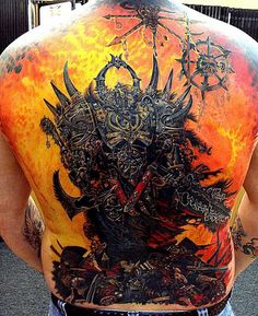 the back of a man's body with tattoos on it and an image of a demon