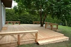 a wooden deck with benches and trees in the background