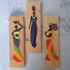 three pieces of art made to look like women in colorful dresses on wooden planks