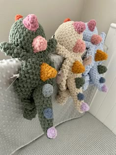 three crocheted stuffed animals sitting on top of a white bed next to each other