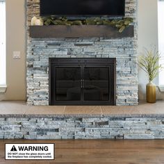 a stone fireplace with a flat screen tv above it and two plants on the mantle