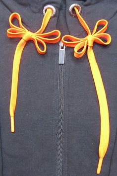 an orange ribbon tied to the side of a black jacket with zippers on it