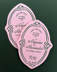 two pink and green wedding save the date stickers on a black surface with white writing