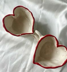 two heart shaped bowls sitting on top of a white sheet