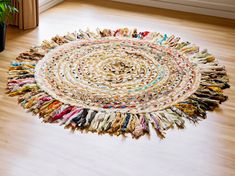 a multicolored round rug on the floor next to a potted plant