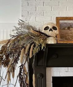 a skull sitting on top of a mantle next to a fire place with dried plants