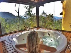 a woman sitting in a large jacuzzi tub on top of a wooden deck