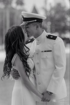 a man in uniform kissing a woman on the cheek while she is wearing a white dress