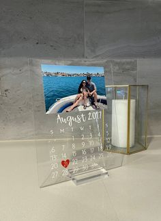 a glass photo frame with a couple sitting on a boat in the water next to a candle