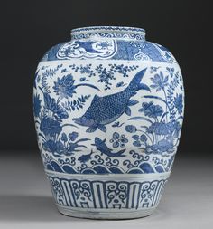 a blue and white vase with fish on it's side, sitting on a table