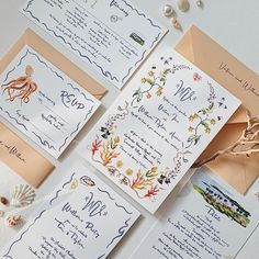 the wedding stationery is laid out neatly on top of each other, with shells and seashells