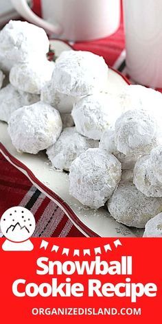 a plate full of snowball cookies next to two mugs