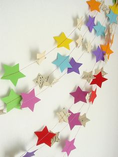 colorful paper stars hanging from strings on a white wall with music notes attached to them