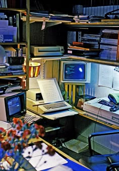 a desk with a laptop computer sitting on top of it next to a book shelf