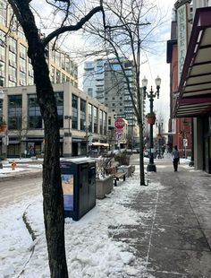 the sidewalk is covered in snow and there are buildings on both sides