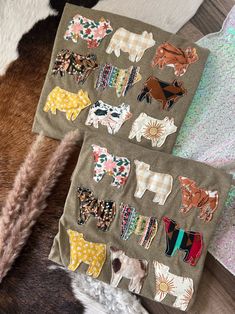 two pieces of fabric with animals on them sitting next to each other in front of a cow skin rug