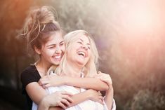 two young women hugging each other outside in the sun with their arms around one another