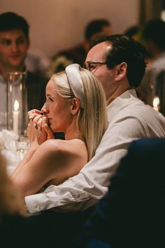 a woman sitting next to a man at a dinner table with other people around her