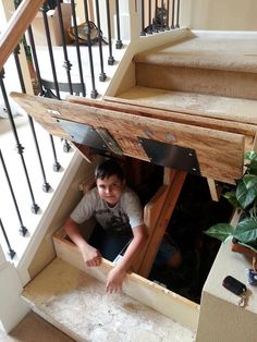 a young man is sitting on the stairs in his home under an open stair case