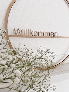 a vase filled with white flowers next to a wooden sign that says willkommen