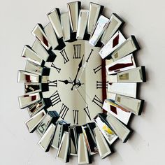 a large mirror clock on the wall with roman numerals and mirrors around it